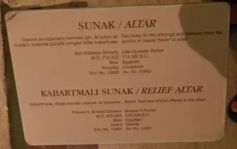 An altar with a symbol of Nefer, a cross on top of an elongated circle, in the middle of two holes